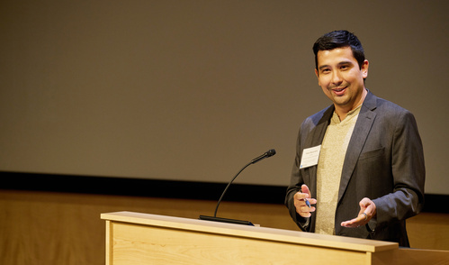 Jason Buenrostro stands behind a podium speaking to an audience.