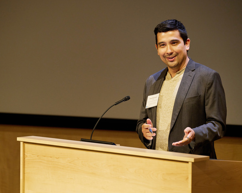 Jason Buenrostro stands behind a podium speaking to an audience.