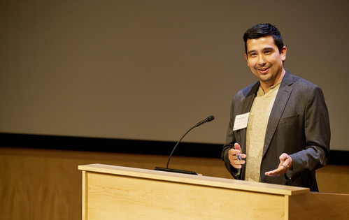 Jason Buenrostro stands behind a podium speaking to an audience.