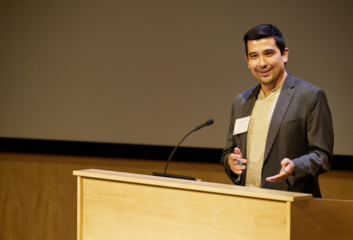 Jason Buenrostro stands behind a podium speaking to an audience.