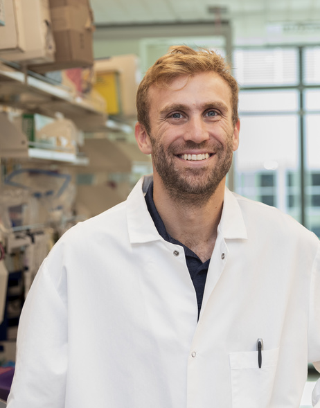 Eric Brown is photographed in a lab wearing a white lab coat.
