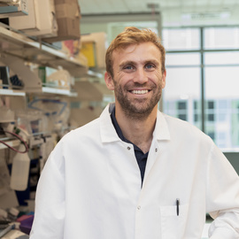 Eric Brown is photographed in a lab wearing a white lab coat.