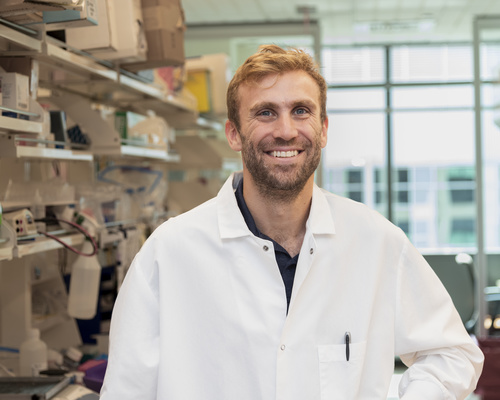 Eric Brown is photographed in a lab wearing a white lab coat.