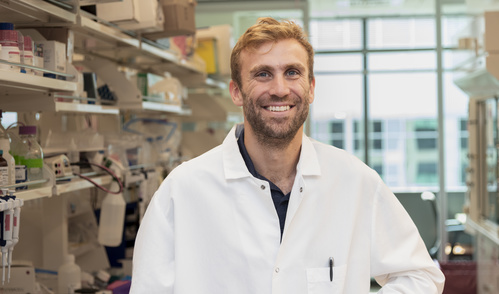 Eric Brown is photographed in a lab wearing a white lab coat.