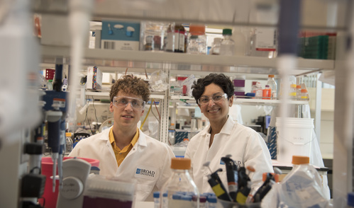 Erik Minikel and Sonia Vallabh stand side-by-side in a lab, wearing lab coats.
