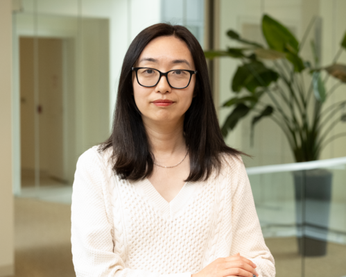 Gail Guo is facing the camera in the Broad Institute building in front of a hallway.