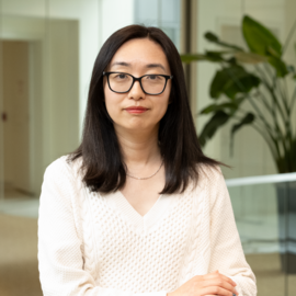 Gail Guo is facing the camera in the Broad Institute building in front of a hallway.
